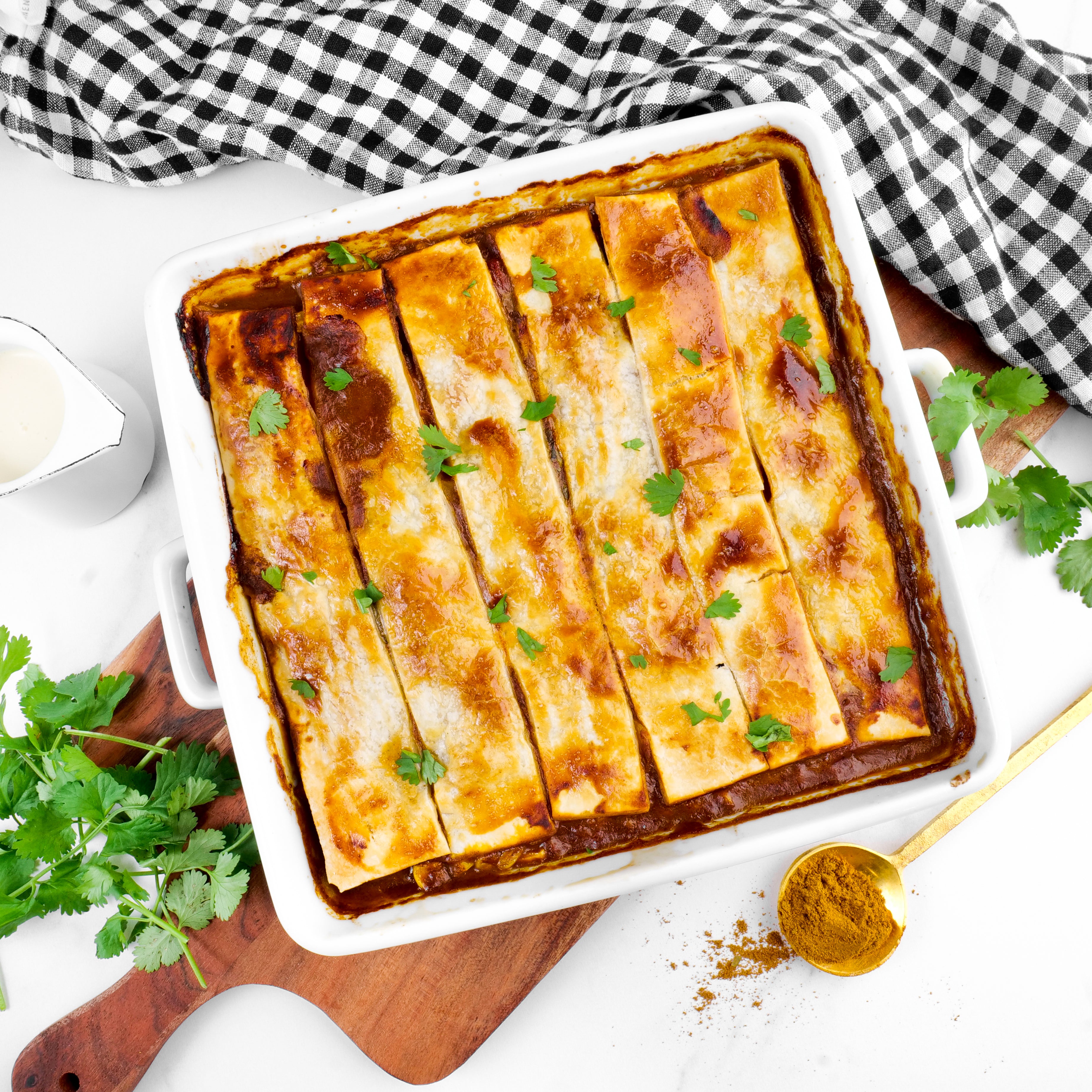 Low FODMAP Butter Chicken Pie garnished with herbs on a white surface with a checkered cloth