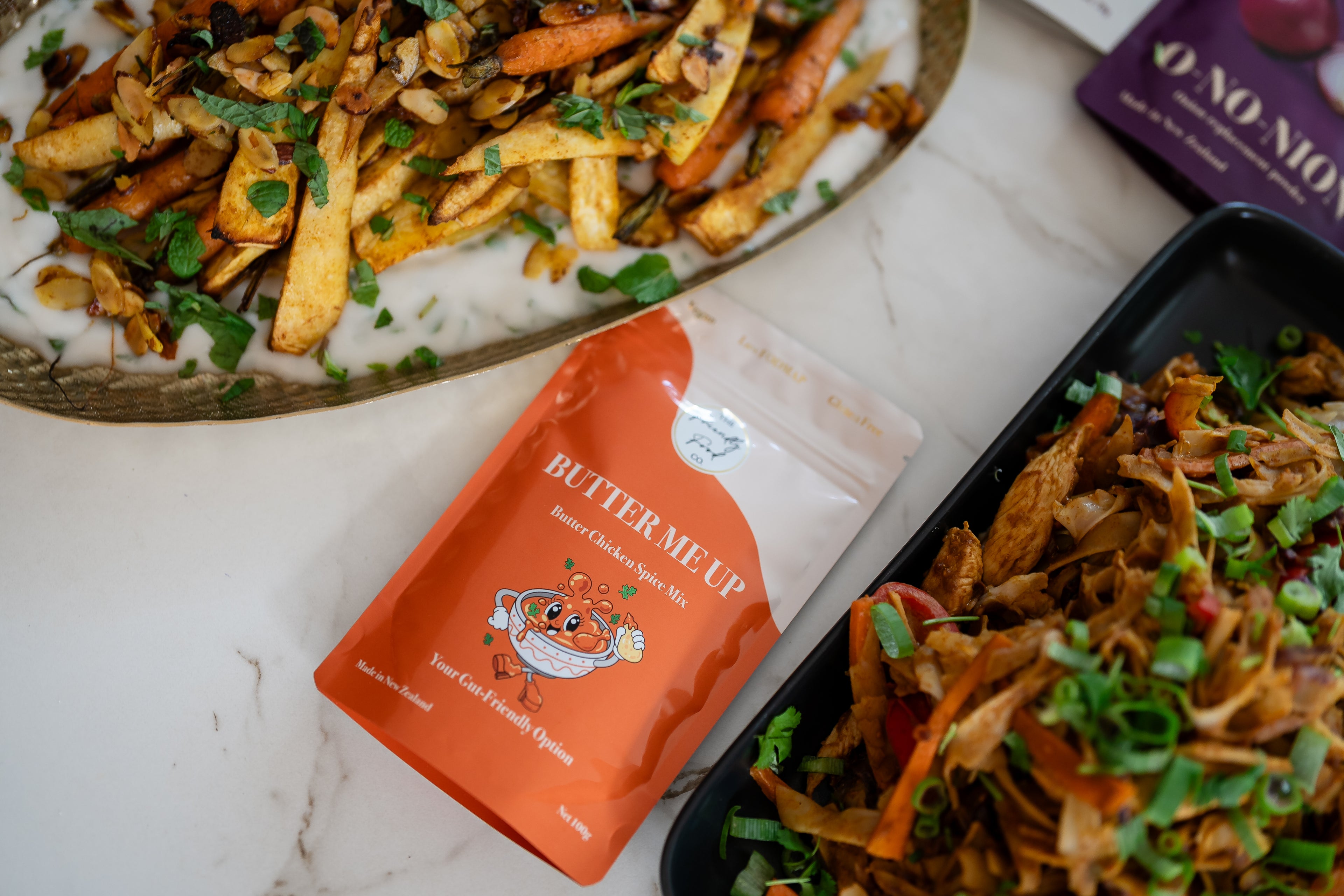 Butter Chicken with a packet of 'Butter Me Up' on a marble surface