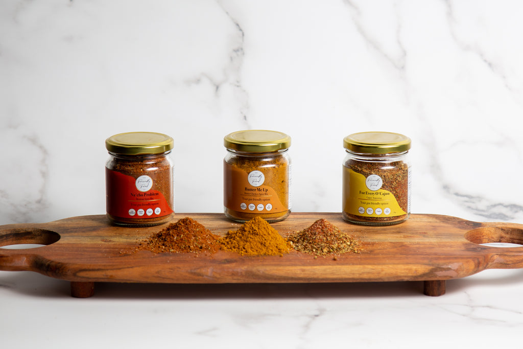 Three jars of The Friendly Food Co low fodmap spices on a wooden tray with a white marble background