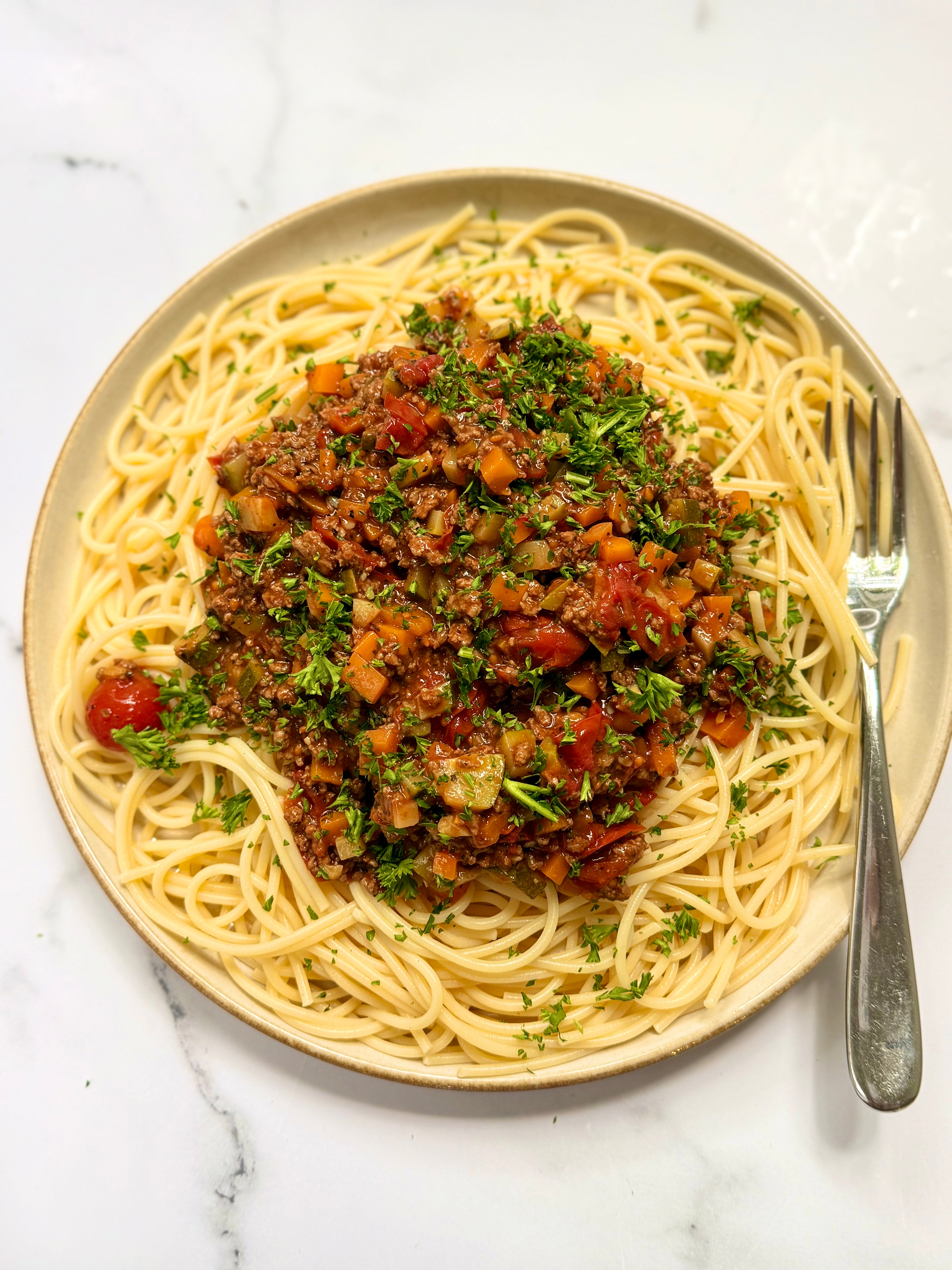Plate of low FODMAP spaghetti bologneseon a marble surface